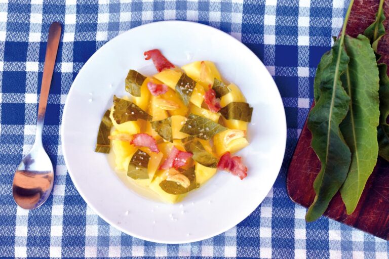 Plato de acederas con patatas y jamón sobre mesa de cuadros