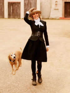 Diane Keaton luciendo un vestido negro y sombrero en un entorno natural