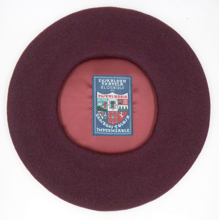 Txapela granate de la marca Elósegui con etiqueta visible. © Elósegui