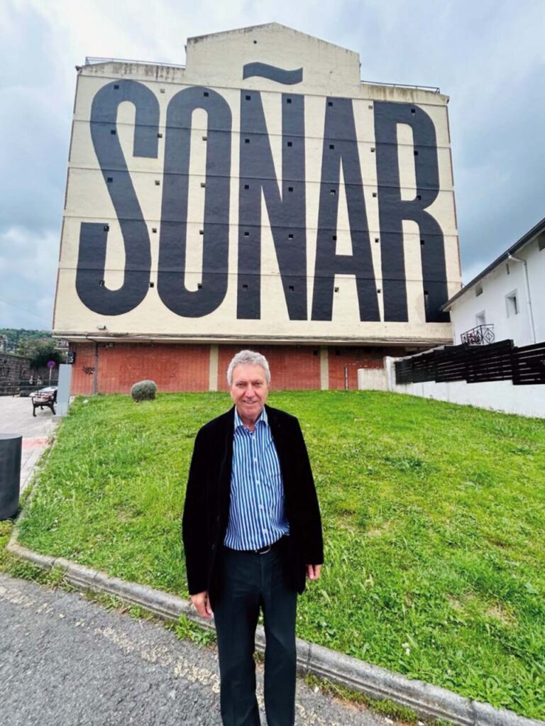Hombre de pie frente a mural que dice SOÑAR en Bilbao