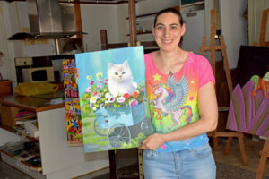 Alazne Mantxa sosteniendo una pintura de un gato en un entorno artístico