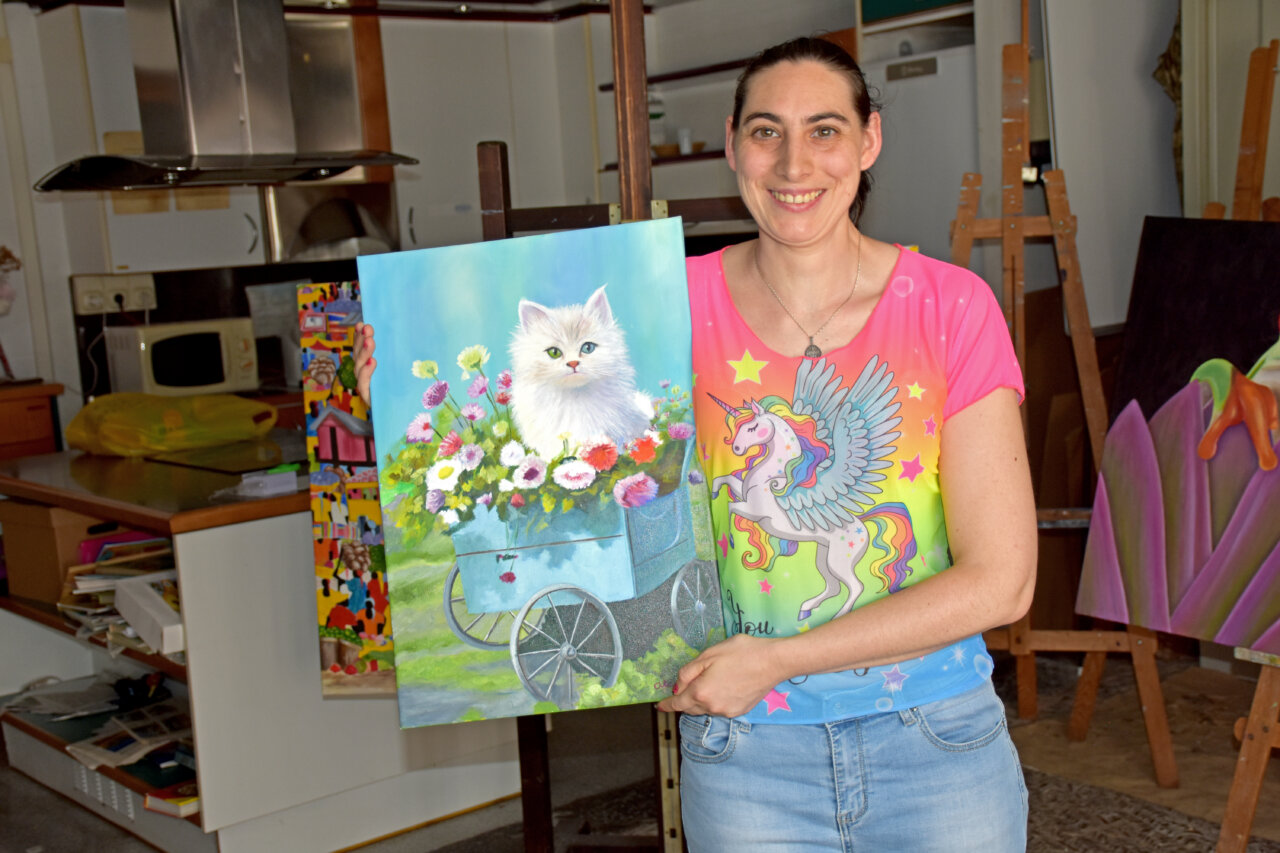 Alazne Mantxa sosteniendo una pintura de un gato en un entorno artístico